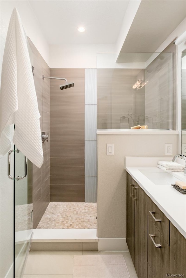 bathroom featuring visible vents, tiled shower, vanity, and tile patterned flooring