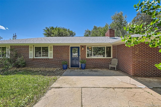 305 Cottonwood Ct, Longmont, CO 80501 - single story home featuring brick siding, a chimney, a patio area, and a shingled roof