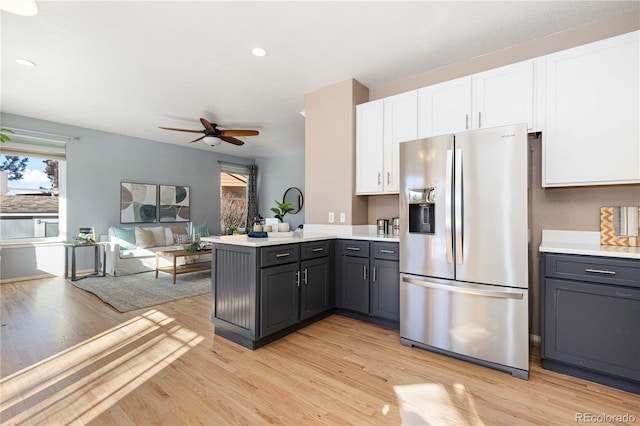 kitchen with kitchen peninsula, stainless steel fridge, ceiling fan, light wood-type flooring, and white cabinets