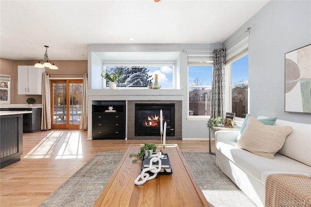 living room featuring a tile fireplace, light hardwood / wood-style flooring, and an inviting chandelier