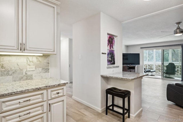795 S Alton Way Unit 4C, Denver, CO 80247 - kitchen featuring open floor plan, decorative backsplash, light stone counters, a breakfast bar area, and a textured ceiling