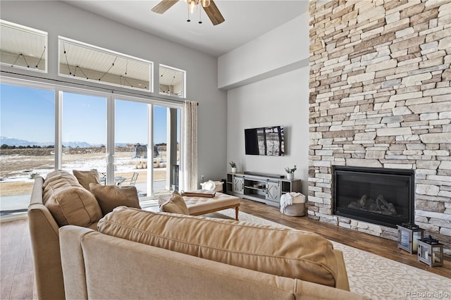 living room featuring ceiling fan, hardwood / wood-style floors, and a fireplace