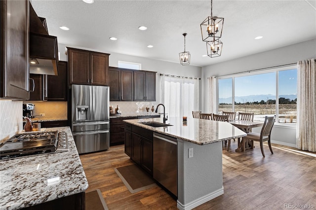 kitchen with appliances with stainless steel finishes, an island with sink, sink, hanging light fixtures, and a mountain view