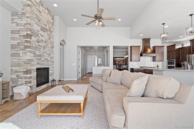 living room with a fireplace, ceiling fan, and light wood-type flooring