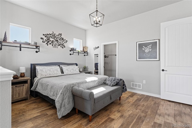 bedroom with hardwood / wood-style flooring, a spacious closet, a chandelier, and multiple windows