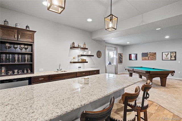 kitchen featuring pendant lighting, sink, stainless steel dishwasher, dark brown cabinets, and light hardwood / wood-style flooring