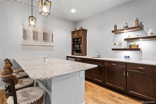 kitchen featuring pendant lighting, sink, a breakfast bar area, a center island, and light hardwood / wood-style floors