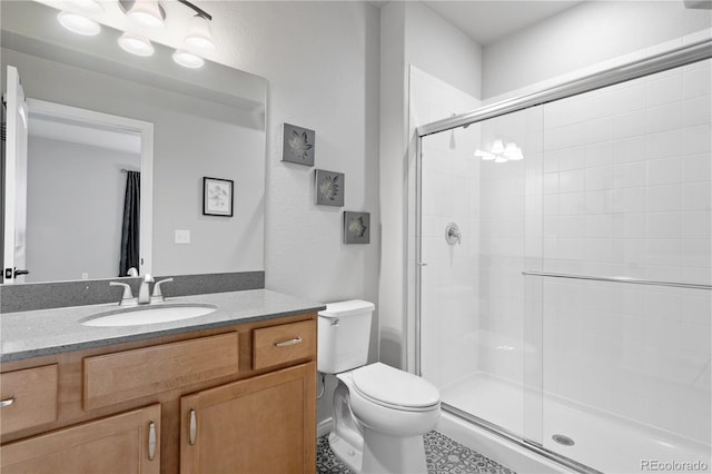 bathroom featuring toilet, vanity, and a shower with shower door