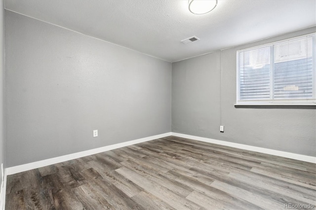 empty room with wood-type flooring and a textured ceiling