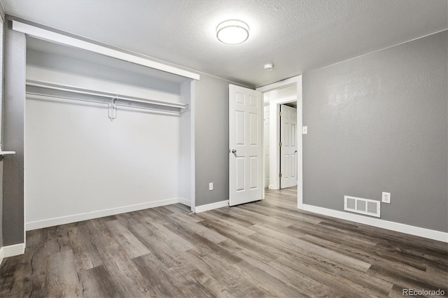 unfurnished bedroom with a textured ceiling, hardwood / wood-style flooring, and a closet