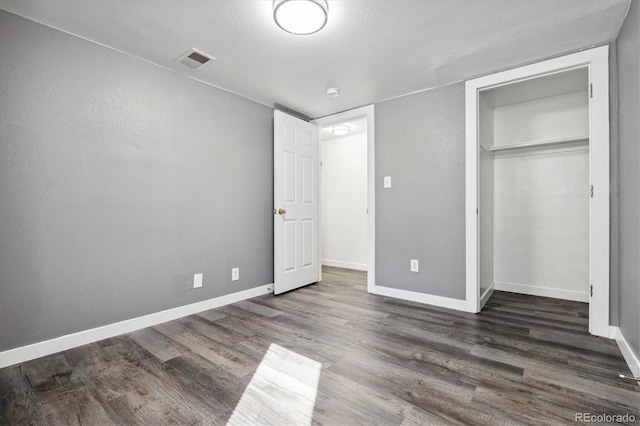 unfurnished bedroom with a closet, dark hardwood / wood-style floors, and a textured ceiling