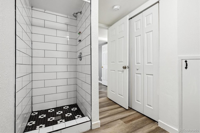 bathroom with a tile shower and hardwood / wood-style floors