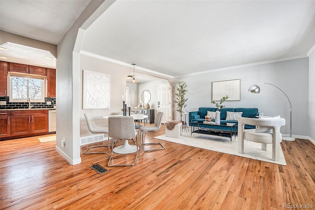 dining space with baseboards, ornamental molding, visible vents, and light wood-style floors