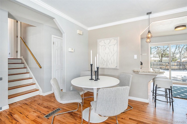 dining area featuring arched walkways, baseboards, stairs, ornamental molding, and light wood finished floors