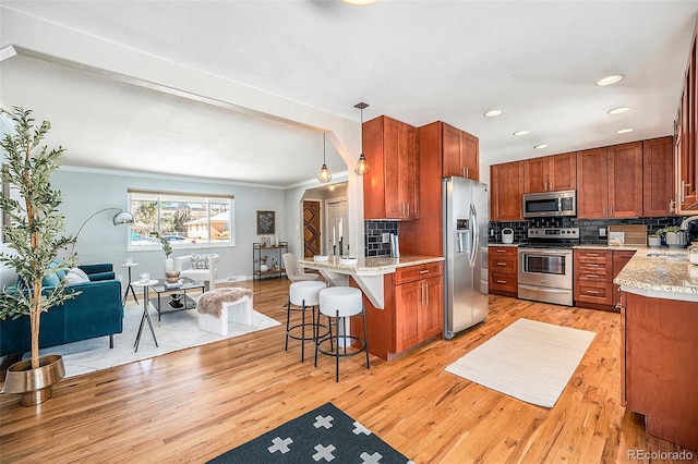 kitchen featuring stainless steel appliances, a breakfast bar, a sink, tasteful backsplash, and pendant lighting