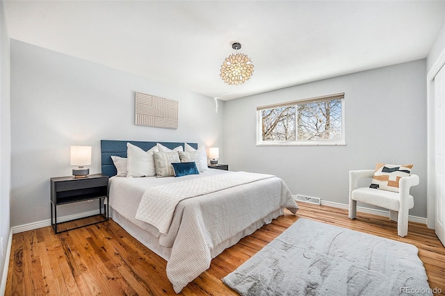 bedroom featuring baseboards, visible vents, and wood finished floors