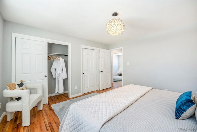 bedroom with baseboards, wood finished floors, and multiple closets