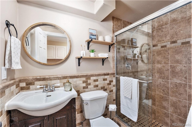 full bath with a stall shower, wainscoting, toilet, vanity, and tile walls