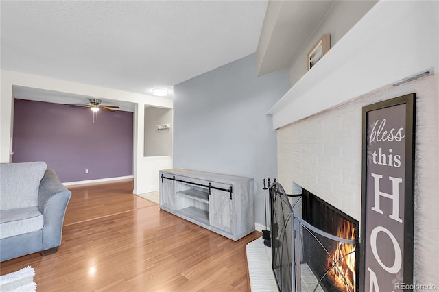 14214 E 1st Dr Unit B08, Aurora, CO 80011 - living room featuring a ceiling fan, light wood finished floors, and a brick fireplace