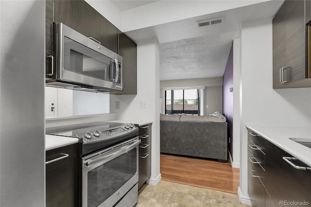 14214 E 1st Dr Unit B08, Aurora, CO 80011 - kitchen featuring stainless steel appliances, light countertops, a textured ceiling, and open floor plan