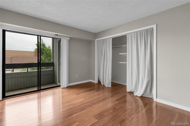 14214 E 1st Dr Unit B08, Aurora, CO 80011 - unfurnished bedroom featuring access to exterior, light wood finished floors, and a textured ceiling