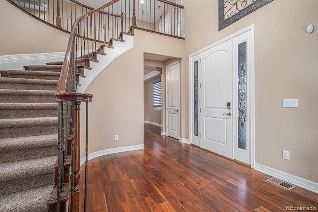 entryway with a towering ceiling and dark wood-type flooring