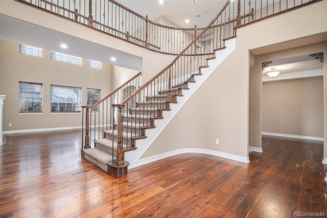 staircase with a high ceiling and hardwood / wood-style floors