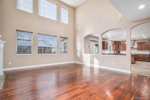 unfurnished living room featuring dark wood-type flooring and a high ceiling