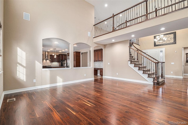 unfurnished living room featuring dark hardwood / wood-style floors and a towering ceiling