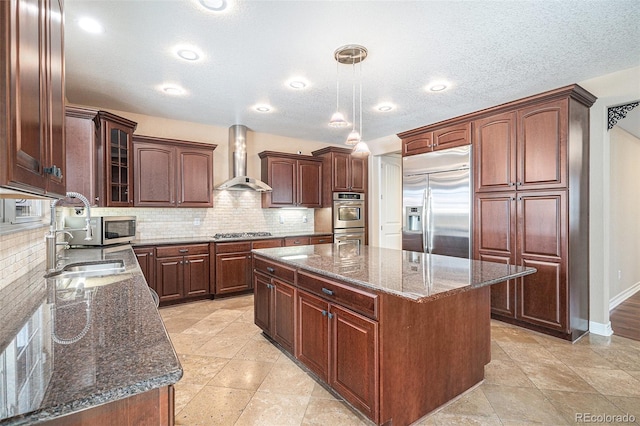 kitchen featuring wall chimney exhaust hood, appliances with stainless steel finishes, tasteful backsplash, decorative light fixtures, and a kitchen island