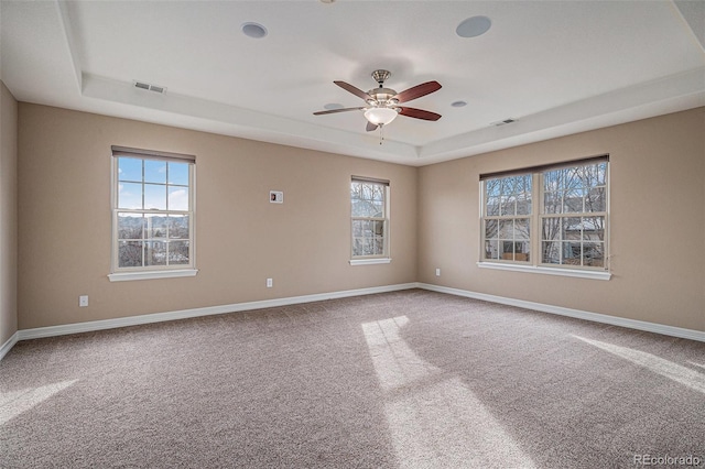 carpeted empty room with a raised ceiling and ceiling fan