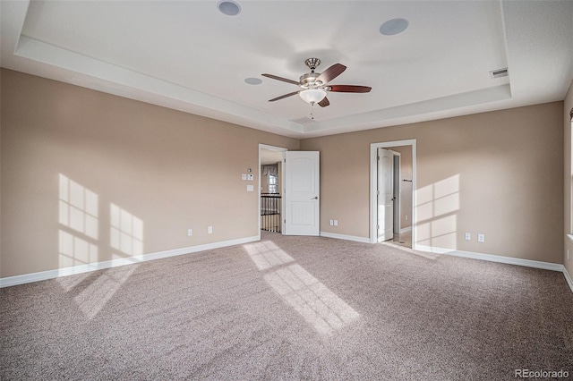 carpeted empty room with a raised ceiling and ceiling fan