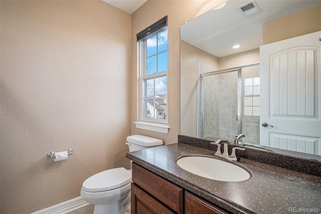 bathroom featuring toilet, a wealth of natural light, an enclosed shower, and vanity