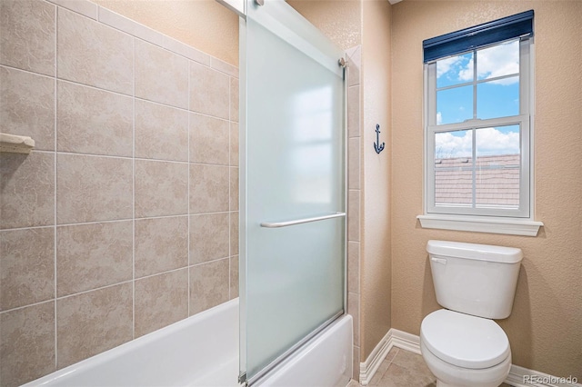 bathroom featuring toilet, tile patterned flooring, and combined bath / shower with glass door