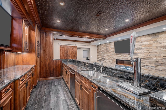 kitchen featuring stainless steel dishwasher, dark stone countertops, sink, and beamed ceiling