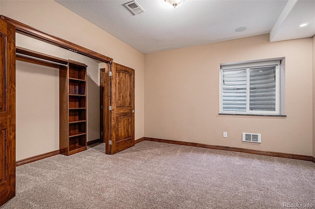 unfurnished bedroom featuring light carpet, a closet, and a textured ceiling