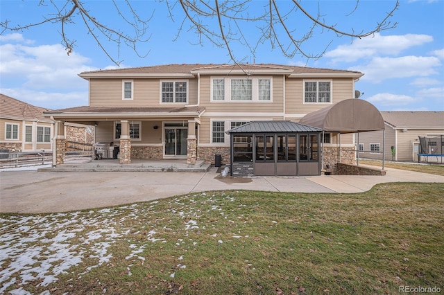 back of property featuring a yard, a trampoline, and a patio