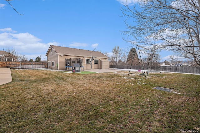 rear view of property featuring a patio area, a trampoline, and a yard