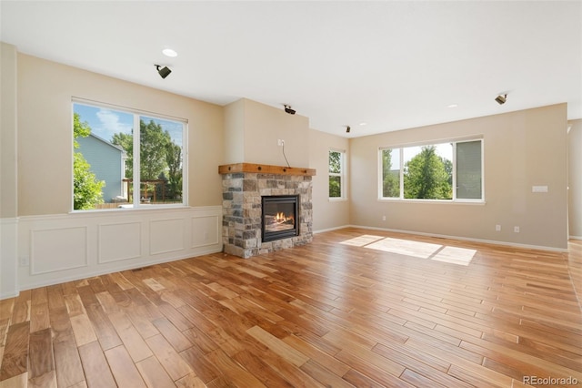 5894 Graphite St, Timnath, CO 80547 - unfurnished living room with light wood finished floors, a fireplace, and a wainscoted wall