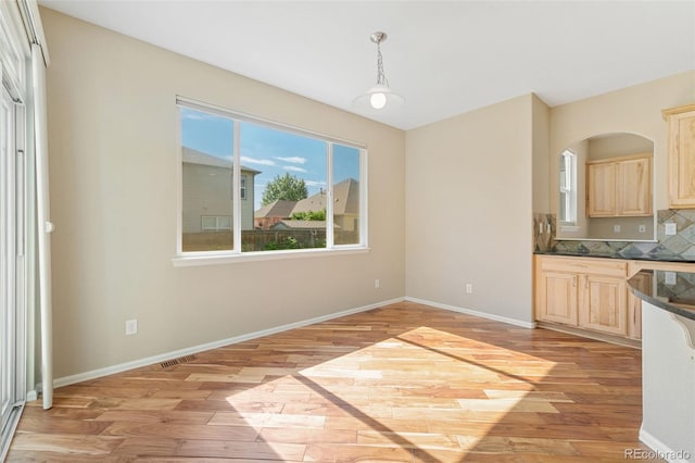 5894 Graphite St, Timnath, CO 80547 - kitchen with light brown cabinets, light wood-style floors, healthy amount of natural light, and dark countertops