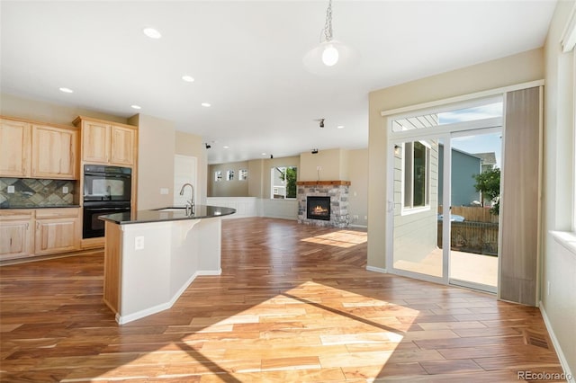 5894 Graphite St, Timnath, CO 80547 - kitchen with light brown cabinetry, dark countertops, wood finished floors, tasteful backsplash, and open floor plan