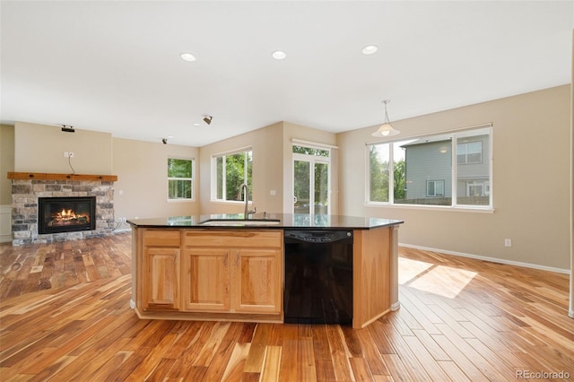 5894 Graphite St, Timnath, CO 80547 - kitchen featuring black dishwasher, light wood-type flooring, dark countertops, a stone fireplace, and recessed lighting