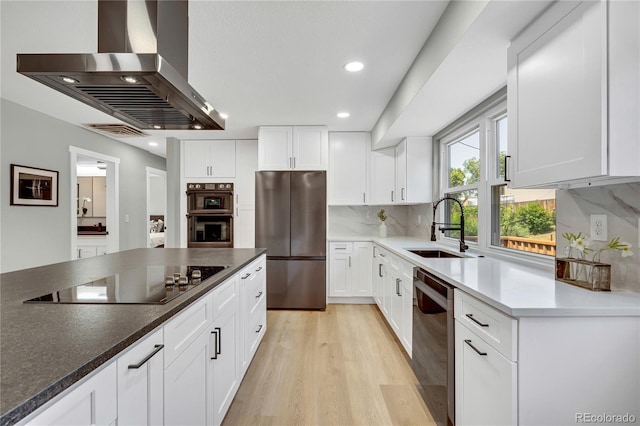 6842 Garland St, Arvada, CO 80004 - kitchen featuring stainless steel appliances, island range hood, light wood-style floors, white cabinets, and backsplash