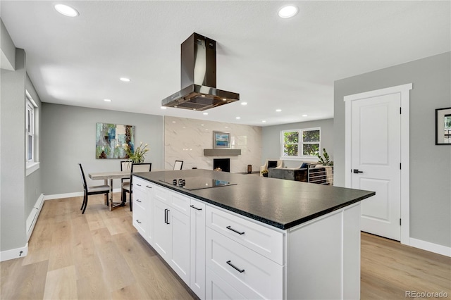6842 Garland St, Arvada, CO 80004 - kitchen with island exhaust hood, black electric cooktop, dark countertops, white cabinetry, and light wood finished floors