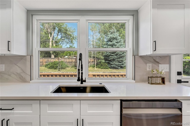 6842 Garland St, Arvada, CO 80004 - kitchen with stainless steel dishwasher, light countertops, white cabinets, and plenty of natural light