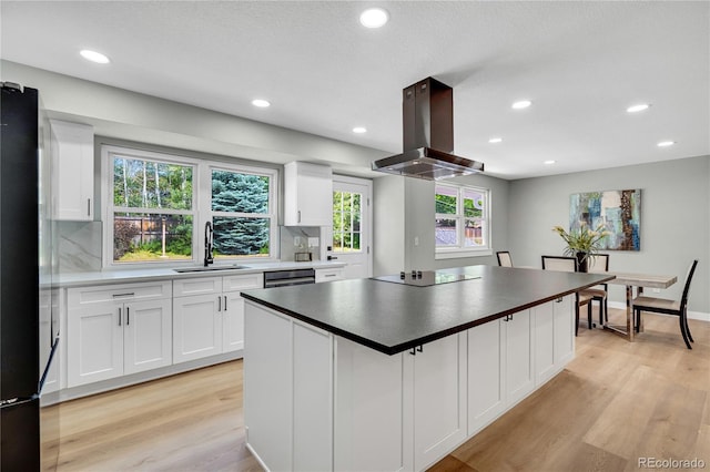 6842 Garland St, Arvada, CO 80004 - kitchen with island exhaust hood, black appliances, light wood-type flooring, white cabinets, and recessed lighting