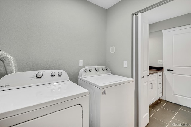 6842 Garland St, Arvada, CO 80004 - laundry area featuring washing machine and dryer, cabinet space, dark tile patterned flooring, and a textured wall