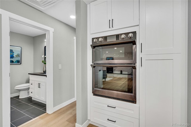 6842 Garland St, Arvada, CO 80004 - kitchen featuring double oven, white cabinetry, and light wood finished floors
