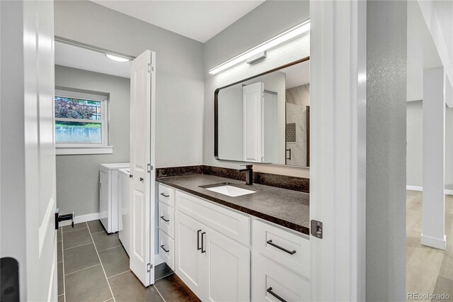 6842 Garland St, Arvada, CO 80004 - full bathroom with washing machine and clothes dryer, vanity, tile patterned floors, and tiled shower