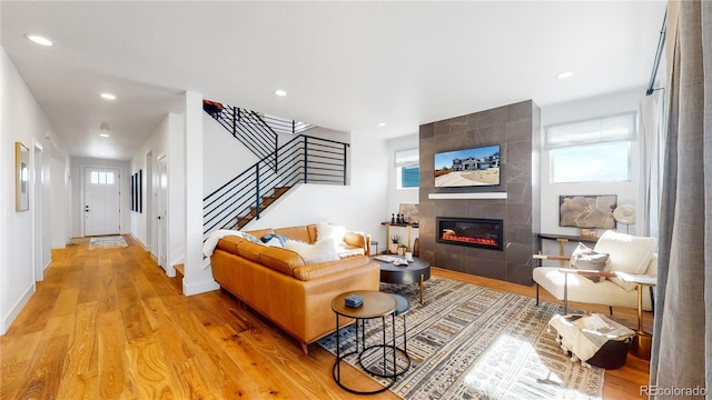 living room featuring plenty of natural light, a tile fireplace, and light hardwood / wood-style flooring